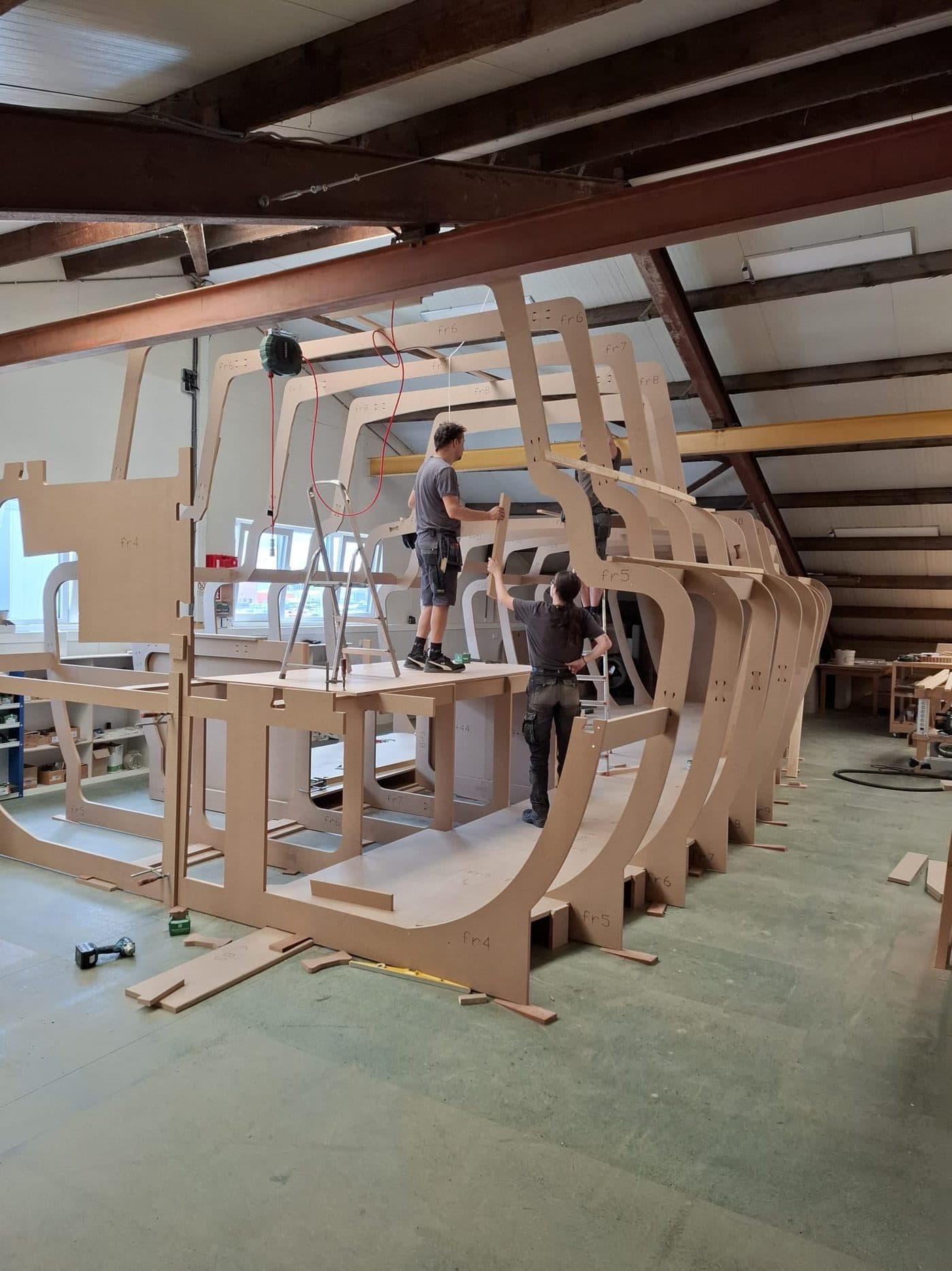 Twee medewerkers bouwen de spanten van een nieuwbouwschip in de werkplaats